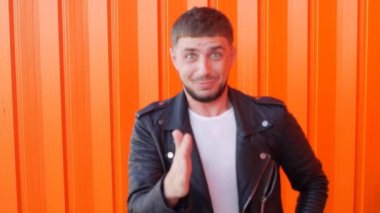 Genç caicasian neşeli adam bir robot gibi hareket eder bir turuncu arka plan, yakın çekim, slo-mo, yaşam biçimi