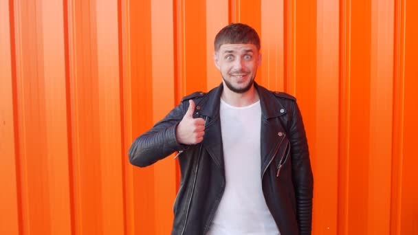 Kaukasischer junger Mann bewegt sich wie ein Roboter und zeigt wie auf orangefarbenem Hintergrund, Nahaufnahme, Zeitlupe — Stockvideo