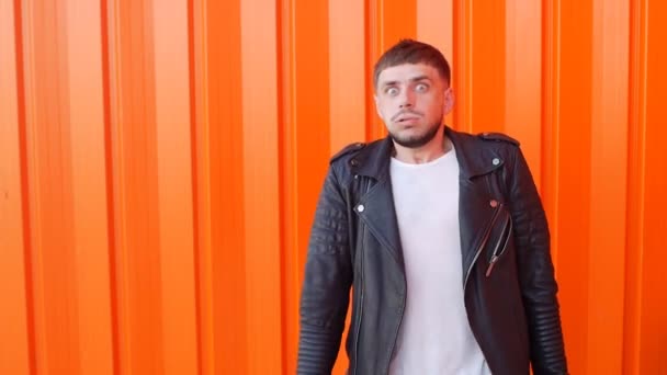 Молодой кавказский человек боится страха, на оранжевом фоне, крупным планом, медленным планом, тревогой — стоковое видео