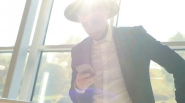Şık beyaz adam siyah takım elbise ve şapka telefon elinde tutuyor ve Havaalanı, yakın çekim, ağır çekim olurken bilgileri okuyun