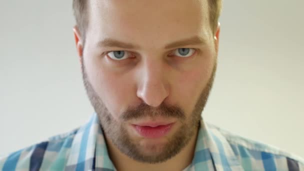 Fashionable young caucasian man with a beard looks into the camera and quickly speaks, close-up, white background, trendy — Stock Video