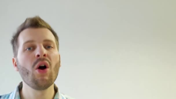 Stijlvolle en trendy jongeman met een baard dansen en zingen op een witte achtergrond, close-up, kopie ruimte — Stockvideo