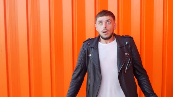 Young caucasian man afraid of fear, on an orange background, close-up, slow-mo, angst, lifestyle — Stock Video