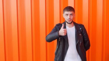 Beyaz genç adam bir robot gibi hareket eder ve gibi gösterir bir turuncu arka plan, yakın çekim, uyuşuk