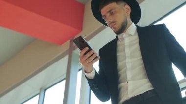 Beyaz adam gezgin istasyonda duran ve seyir telefon, yakın çekim, ağır çekim, viator bir şapka