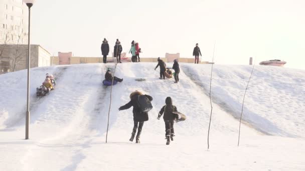 Bobruisk, Vitryssland - 12 januari 2019: Barn på en solig frostig dag rida från en snow hill, vinter, långsamma mo — Stockvideo