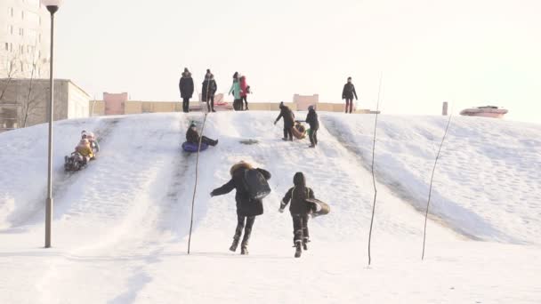 BOBRUISK, BELARO - 12 GENNAIO 2019: Bambini in giornata soleggiata e ghiacciata da una collina innevata, inverno, slow mo — Video Stock