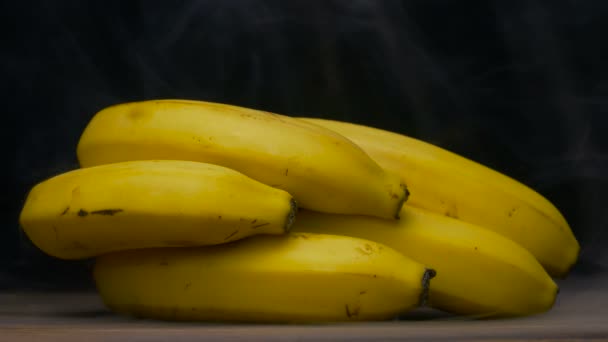 Bunch of ripe Cavendish bananas are on the table in cold, steam from frost, cloese up 4K — Stock Video