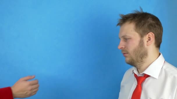 Een bebaarde man in een wit overhemd en stropdas houdt vast aan het hoofd van het probleem, en koopt van alcohol voor geld, blauwe achtergrond — Stockvideo