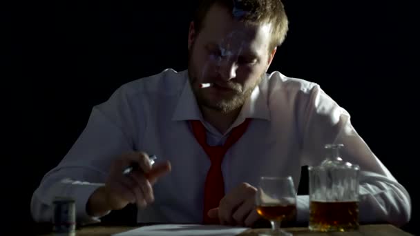 Мужчина бизнесмен с бородой курит и нервничает, принимает алкоголь, сомневается в подписи документов — стоковое видео