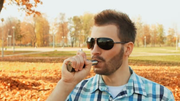 Bärtiger Mann inhaliert Dampf einer E-Zigarette und pustet eine Dampfwolke — Stockvideo