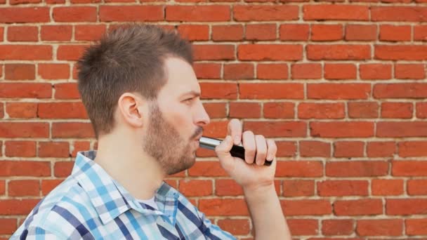 Bearded vaper smokes an electronic cigarette and blows a cloud of vapor — Stock Video