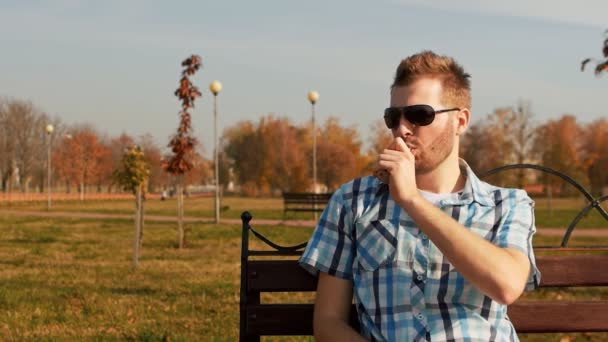 Uomo barbuto fumare una sigaretta elettronica e soffia una nuvola di vapore — Video Stock