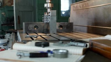 Kasnak, ölçme araçları, üretim, küçük işletme tablo yalan üzerinde bir delik delme makinesi arka planda metal parçalar ile çalışmak için özel bir atölye matkaplar