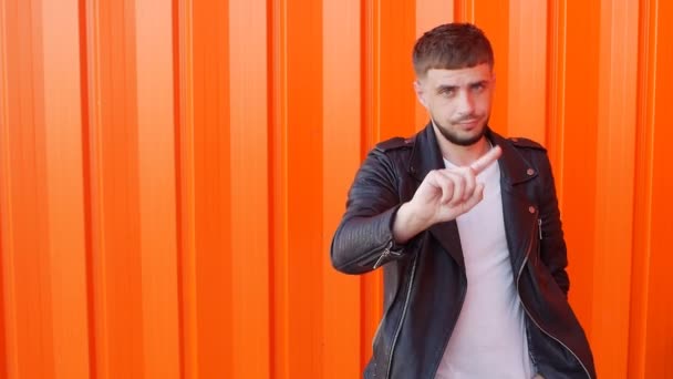 Joven caucásico con barba agitando el dedo y mostrando prohibición, negación, fondo naranja, slow-mo — Vídeos de Stock