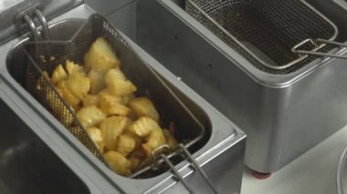 Bir restoran, önemsiz ve yağlı gıdalar, Lokanta, yakın çekim, ağır çekim bir fritöz patates dilimleri pişirme