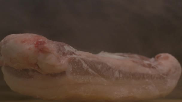 A piece of fresh frozen pork on a black background from which there is frosty freshness and evaporation, close-up, 4k — Stock Video