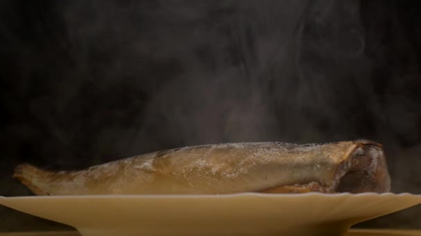 Тарілка з замороженою рибою на чорному тлі, з якої є морозна свіжість і випаровування, крупним планом, 4K — стокове відео