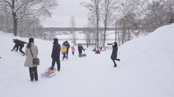 BOBRUISK, BELARO - 6 GENNAIO 2019: Persone e bambini viaggiano su una slitta o su un tubo da una montagna innevata in inverno, al rallentatore — Video Stock