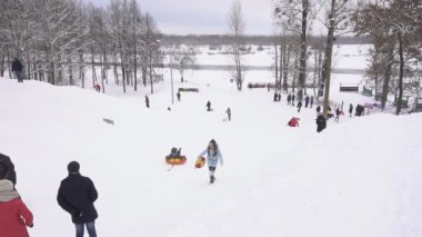 Bobruisk, Belarus - 6 Ocak 2019: İnsanlar ve çocuklar binmek bir kızak veya kış, ağır çekim, çocuk karlı bir dağ üzerinden boru