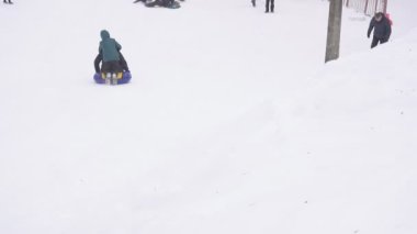 Bobruisk, Belarus - 6 Ocak 2019: Bir çocuk babası kışın karlı bir dağ borulama, yavaş mo üzerinde sürme