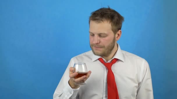 En ung man med ett skägg i vit skjorta och slips håller ett glas med alkohol och vägrar alkohol, alkoholberoende, anti alkohol kodning — Stockvideo