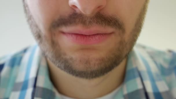 Hombre barbudo sonríe a la cámara, los labios de cerca, fondo blanco, de moda — Vídeos de Stock