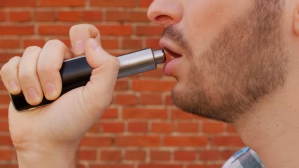 Ansiktet av en man med ett skägg som röker vape, närbild, tegelvägg, långsamma-mo, livsstil — Stockvideo