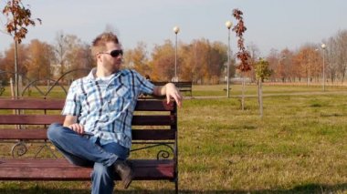 Serin beyaz adam siyah gözlük oturur bir tezgah ve beceriksizce sigara vape, yavaş hareket, boşluk, moda kopya