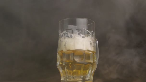 Verdrehtes Bierglas, in das frisches Bier ausgeschenkt wird, Rauch, Frische, Nahaufnahme, schwarzer Hintergrund, Zeitlupe, Kühle — Stockvideo