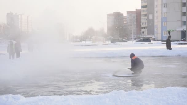 En man häller vatten över en vinter skridskor isbanan, långsamma mo, stadion — Stockvideo