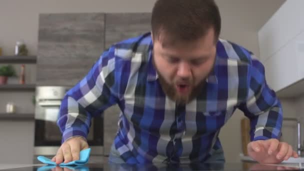 Fat man with a beard rubs the stove in the kitchen, close-up, face, slow-mo, housecleaning — Stock Video
