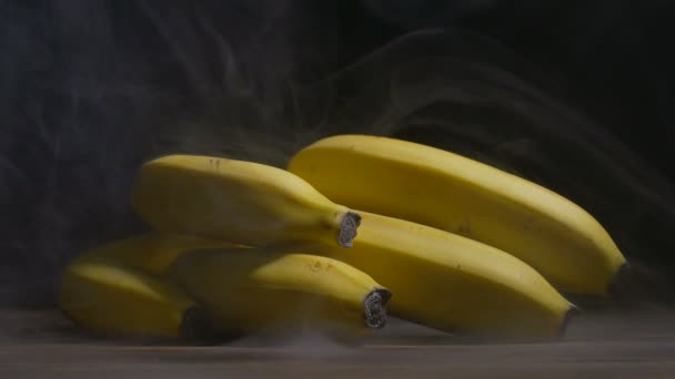 Bunch of Cavendish bananas are on the table in cold, steam from frost in slowmo, cloese up — Stock Video