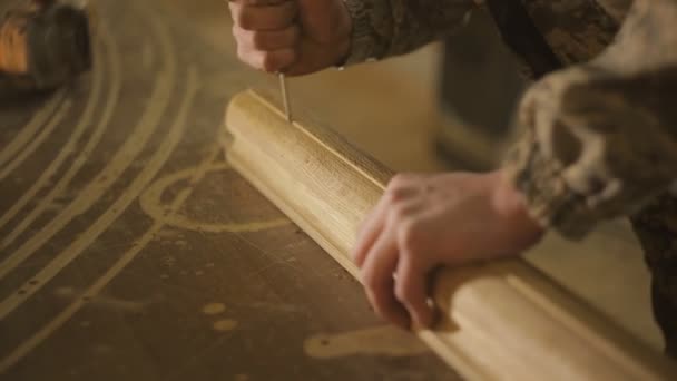 Een timmerman timmerman uitvoert met behulp van een speciaal gereedschap, Fietsen, geeft een ruwheid op een houten product, werkman — Stockvideo