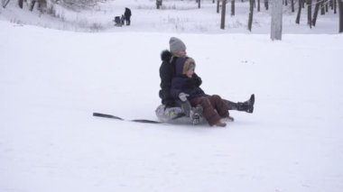 Bobruisk, Beyaz Rusya - 6 Ocak 2019: Kadın çocuk ile bir boru karlı bir dağ, yavaş mo sürmek.