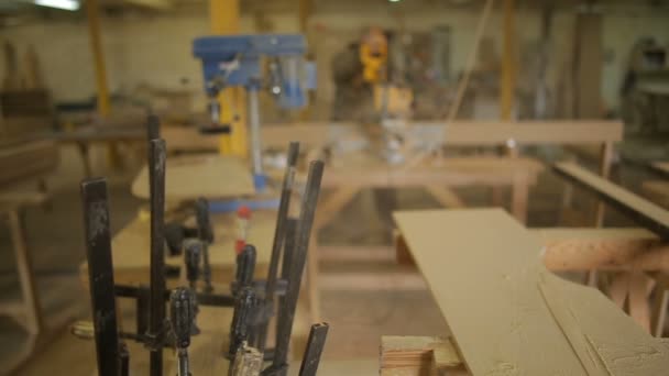 Fokus auf F-Klemmen oder Stabklemmen und Tischler- oder Tischlerarbeiten in der Möbelwerkstatt im Hintergrund — Stockvideo