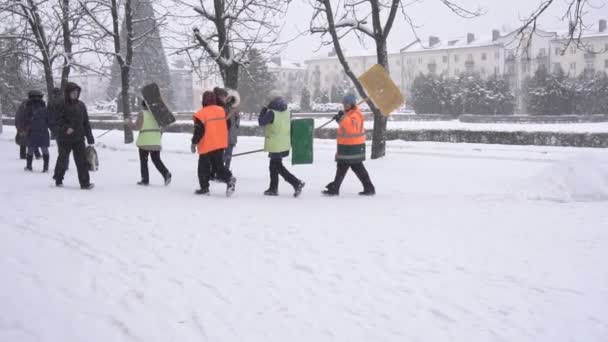 BOBRUISK, BELARUS - 14 DE ENERO DE 2019: Los conserjes en chalecos de señal con palas pasan por la ciudad de invierno, en cámara lenta — Vídeos de Stock