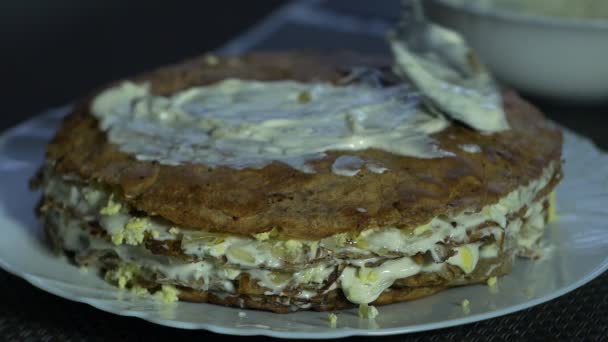 Девушка готовит печеночный торт к празднику, мажет майонез на корочке торта, крупным планом, медленным планом — стоковое видео