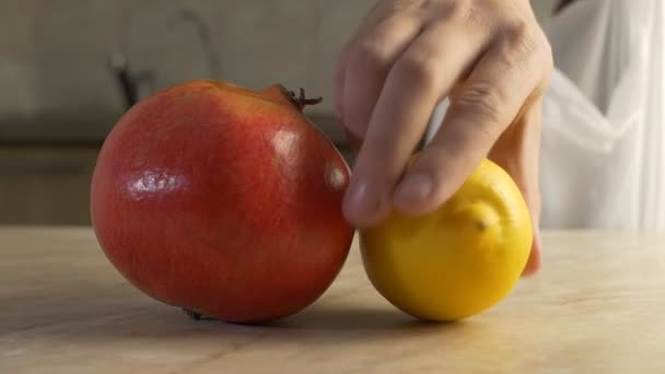 En man vylazhivaet på bordet frukt köpt i butik, bananer, Granatäpplen och persimon med citron, närbild, Slowmotion — Stockvideo