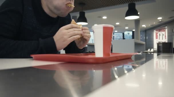 Pria mengisi mulutnya dengan makanan cepat saji, mulut penuh chiken burger atau hamburger dalam gerakan lambat — Stok Video