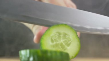 duman yavaş hareket tablosunda Yeşil taze salatalık dilimleri bıçak kesiyor