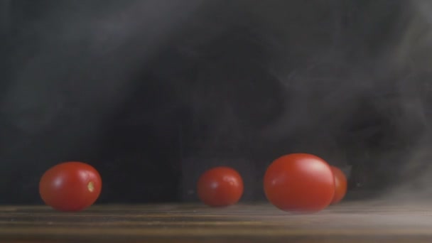 Красные помидоры или помидоры Черри ролл по столу в дыму в slowmo — стоковое видео