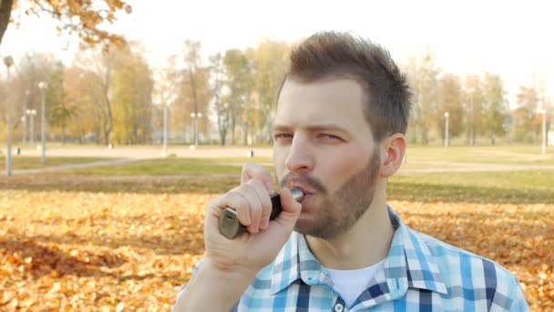 Stijlvolle en trendy man met een baard vape en glimlachend, kijken naar de camera, close-up, slow-mo, lifestyle — Stockvideo