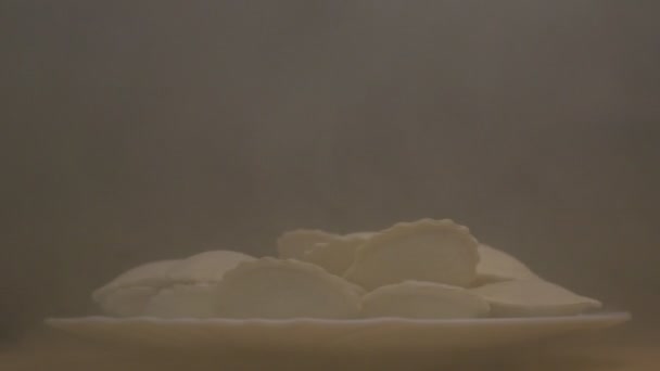 Piastra con gnocchi congelati rotanti su fondo nero da cui soffia freddo ed evaporazione, primo piano, semilavorato, rallentatore — Video Stock