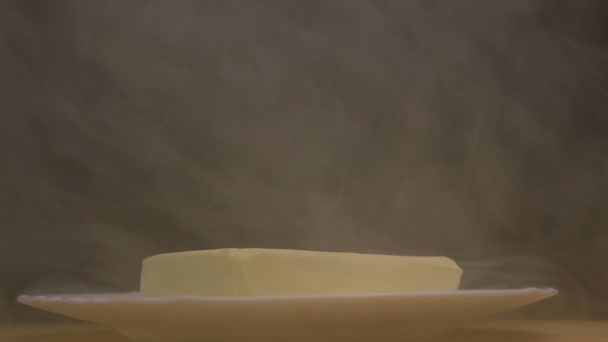 Manteiga congelada que gira sobre um fundo preto a partir do qual há uma névoa gelada e frescura, close-up, câmera lenta — Vídeo de Stock