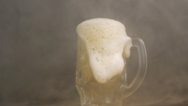 Скрученный пивной стакан, в котором свежее пиво наливается в туман, крупным планом, черным фоном, замедленным движением, ветреностью, солодом — стоковое видео