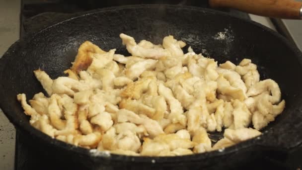 Slowmo pieces of chicken meat are fried or cooked in frying pan or skillet in restaurant kitchen on gas stove — Stock Video