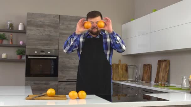 Un homme sérieux avec une barbe et des oranges dans une cuisine moderne, au ralenti, bio — Video