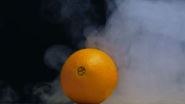 Granja naranja está sobre la mesa y el humo o vapor sopla por detrás en slow mo, primer plano, espacio de copia — Vídeos de Stock