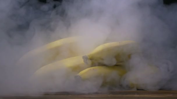 Ein Bündel höhlentauglicher Bananen liegt auf dem Tisch, Rauch weht im Slowmo von hinten, Nahaufnahme — Stockvideo